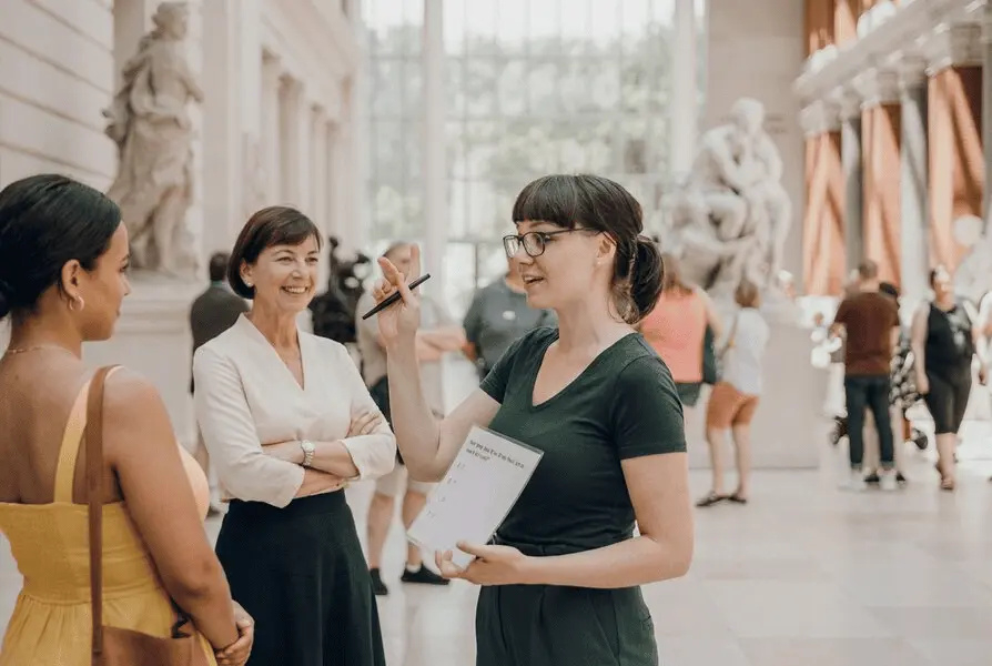 Tour Guide zeigt Teilnehmern Sehenswürdigkeiten bei Stadtführung und nutzt Tablet zur Ticketkontrolle