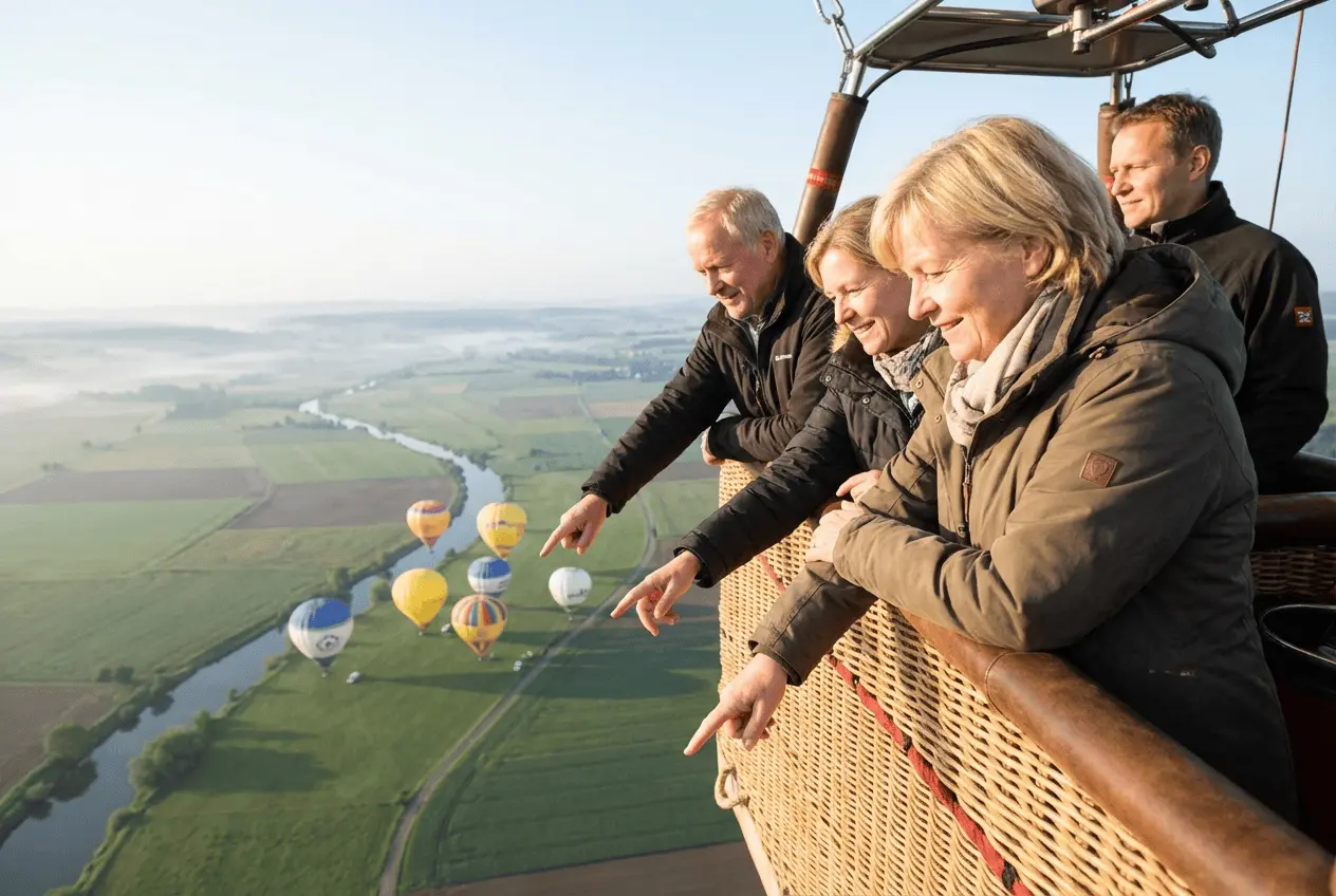 Startender Heissluftballon mit Passagieren im Korb bei Sonnenaufgang